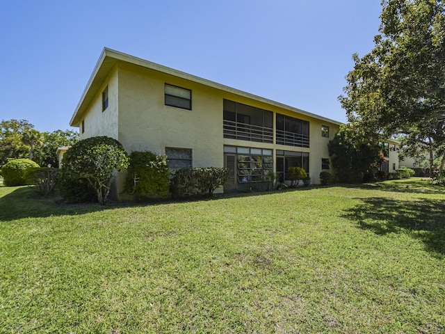 rear view of property featuring stucco siding and a yard