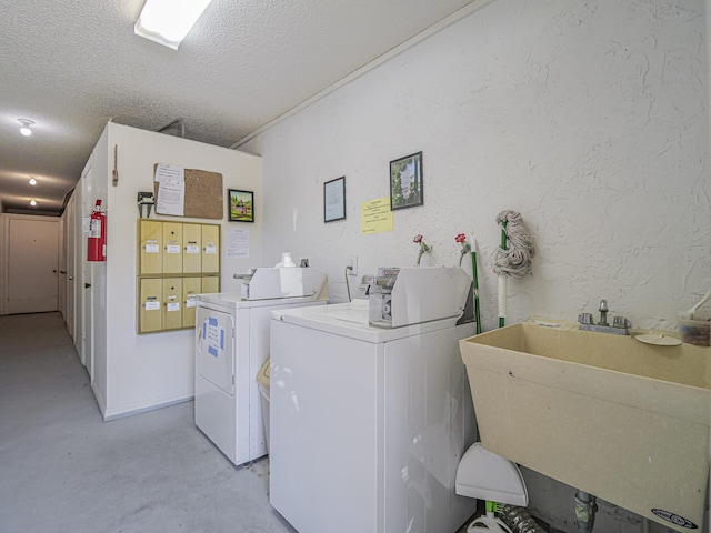 shared laundry area featuring washer and clothes dryer, a sink, a textured ceiling, and a textured wall