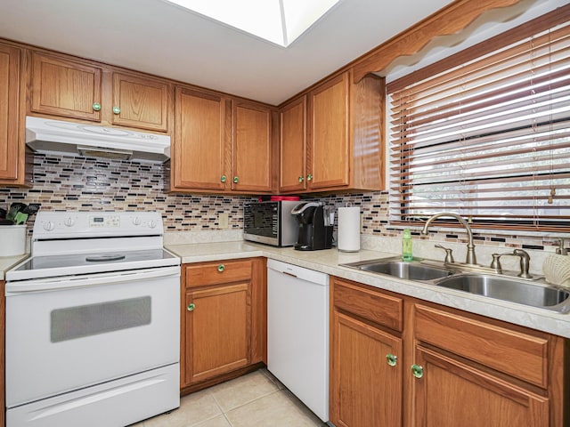 kitchen with white appliances, light tile patterned flooring, a sink, light countertops, and under cabinet range hood