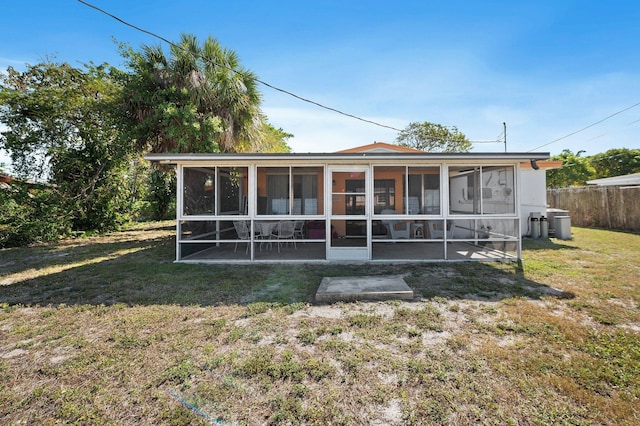 back of property featuring a sunroom, a lawn, and fence