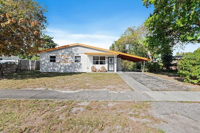 view of front facade with a front lawn, an attached carport, driveway, and fence