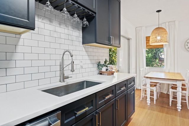 kitchen with stainless steel dishwasher, light countertops, tasteful backsplash, and a sink