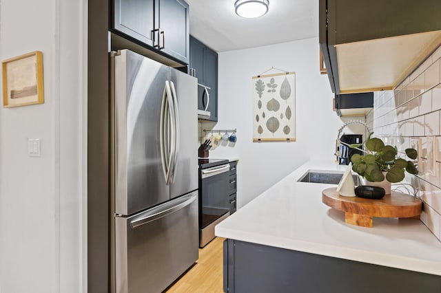 kitchen with light wood finished floors, stainless steel appliances, light countertops, and a sink