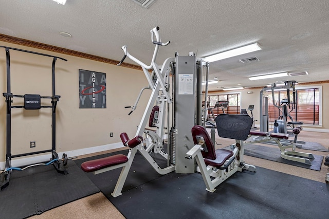 exercise room with baseboards, visible vents, and a textured ceiling