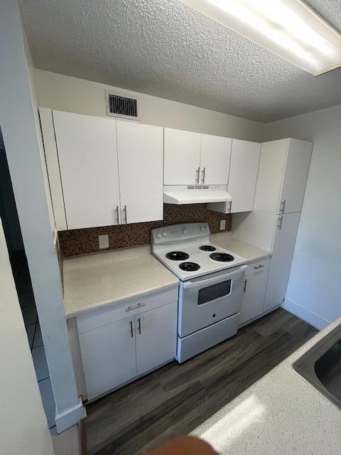 kitchen featuring visible vents, white electric stove, light countertops, under cabinet range hood, and white cabinetry