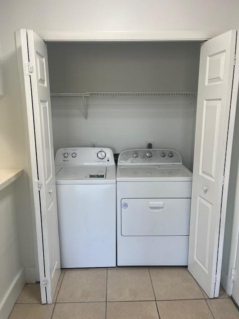 laundry room with separate washer and dryer, light tile patterned flooring, and laundry area