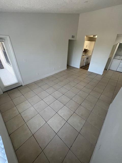 spare room with light tile patterned floors, visible vents, baseboards, and a textured ceiling