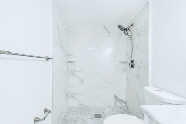 full bath with a marble finish shower and toilet