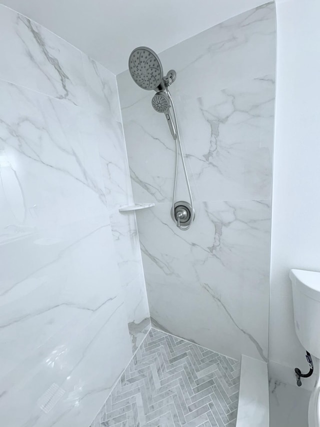 bathroom with a marble finish shower and toilet