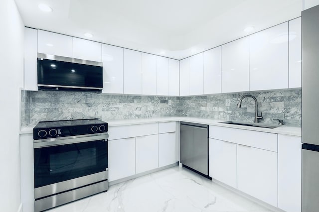 kitchen with a sink, light countertops, appliances with stainless steel finishes, white cabinetry, and modern cabinets