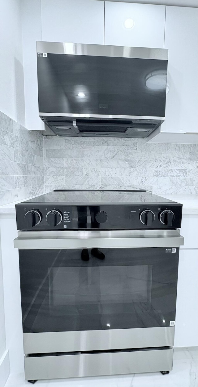 interior details with backsplash, light countertops, appliances with stainless steel finishes, white cabinetry, and modern cabinets