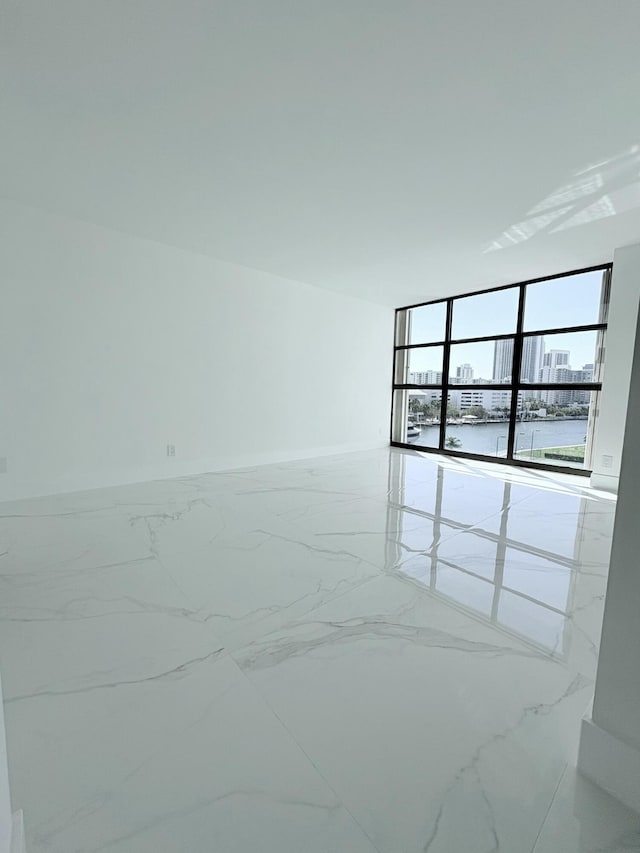 spare room with baseboards, marble finish floor, and floor to ceiling windows