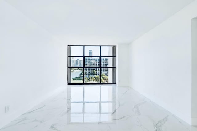 unfurnished room with baseboards and marble finish floor