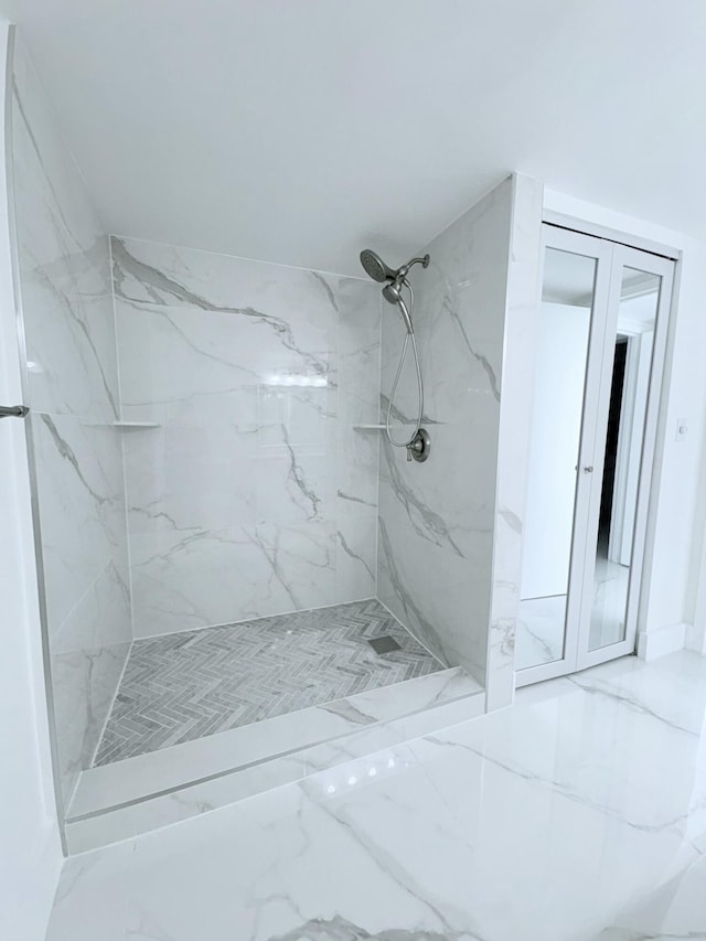 full bath with a marble finish shower and marble finish floor