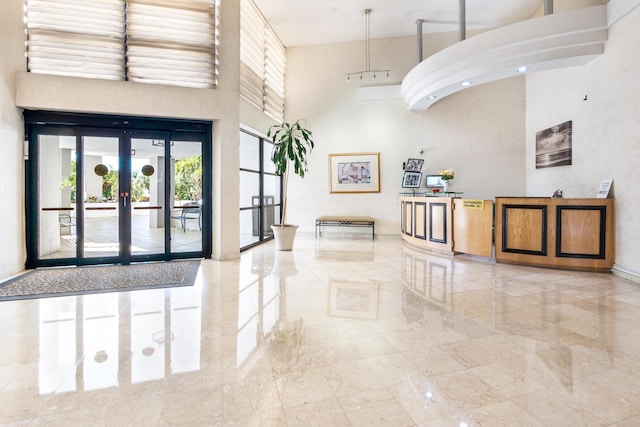 interior space featuring marble finish floor, french doors, and a high ceiling