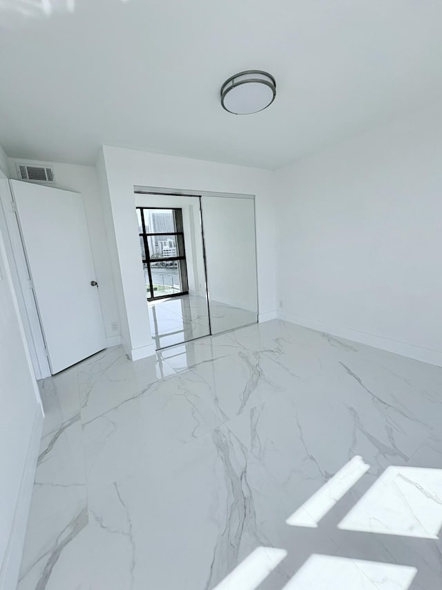 bedroom with a closet, visible vents, marble finish floor, and baseboards