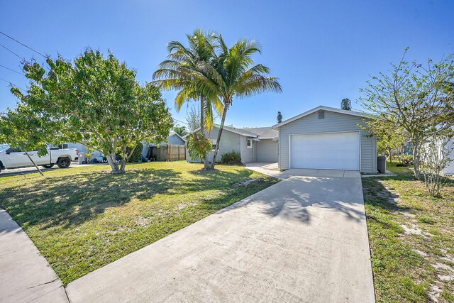 ranch-style home featuring a front lawn, an attached garage, fence, and driveway