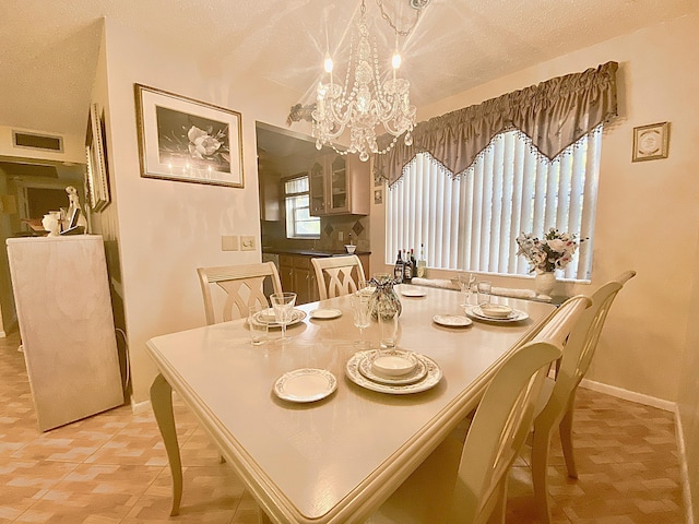 dining space featuring a notable chandelier, visible vents, a textured ceiling, and baseboards