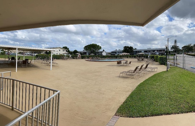 view of community with a patio area, a yard, and fence