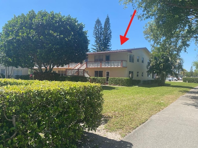 view of property exterior featuring a yard, a balcony, and stucco siding