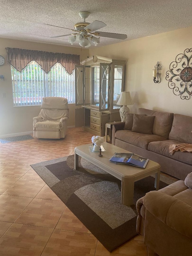 living room with tile patterned floors, baseboards, a textured ceiling, and a ceiling fan