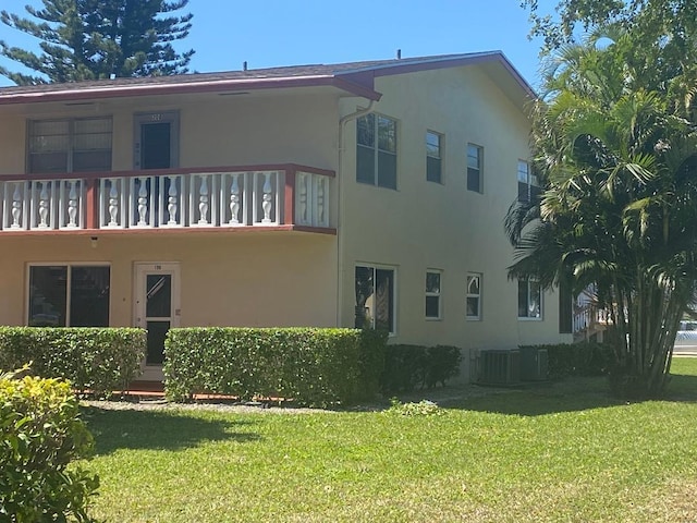 exterior space featuring a balcony, stucco siding, and a yard