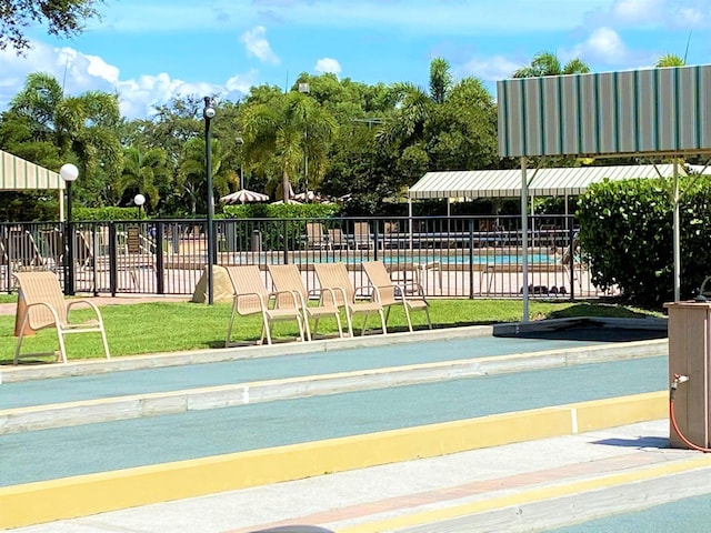 surrounding community with a lawn, a pool, and fence