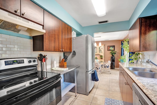 kitchen with under cabinet range hood, a sink, stainless steel appliances, light countertops, and light tile patterned floors