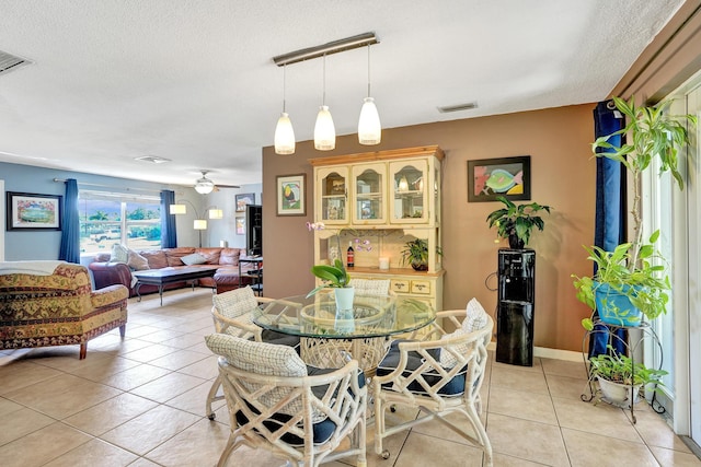 dining room featuring light tile patterned floors, visible vents, a textured ceiling, and a ceiling fan