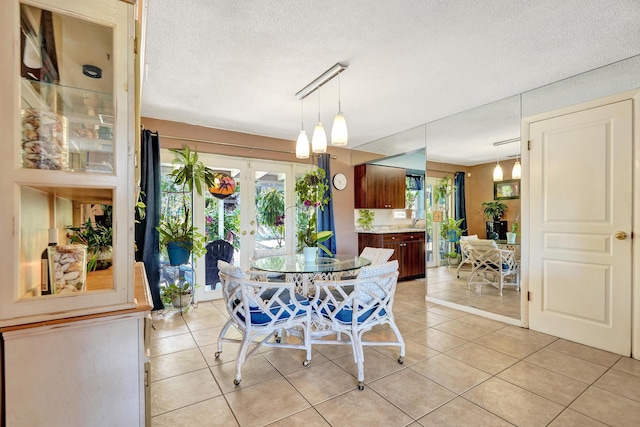 dining space with light tile patterned flooring, french doors, and a textured ceiling