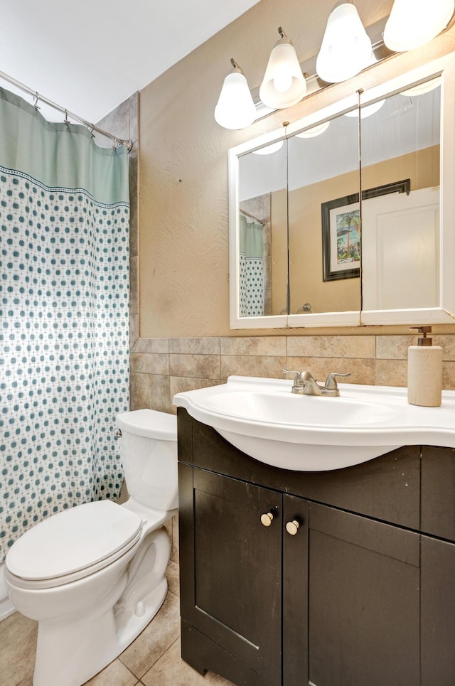 bathroom with tile patterned floors, a shower with curtain, toilet, tile walls, and vanity