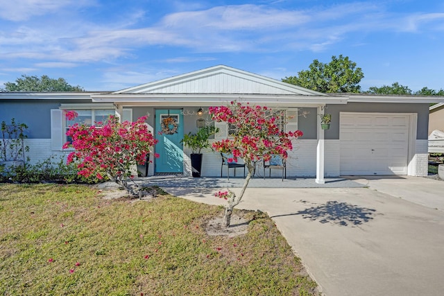 ranch-style home with a porch, an attached garage, concrete driveway, and a front yard