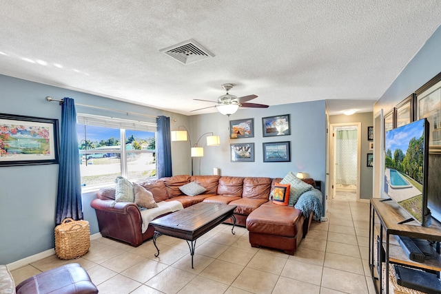 living room with visible vents, baseboards, ceiling fan, light tile patterned flooring, and a textured ceiling