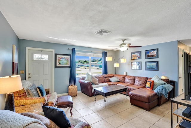 living area featuring a ceiling fan, baseboards, visible vents, light tile patterned flooring, and a textured ceiling