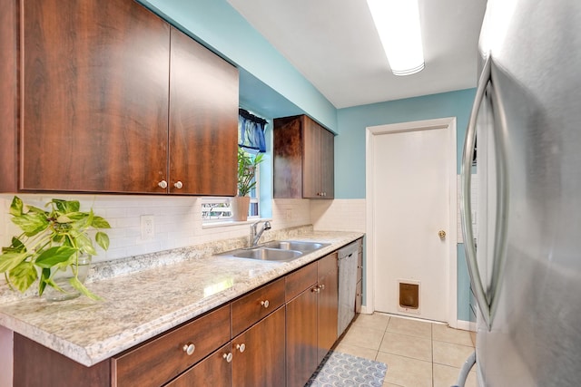 kitchen with light tile patterned floors, decorative backsplash, stainless steel appliances, and a sink