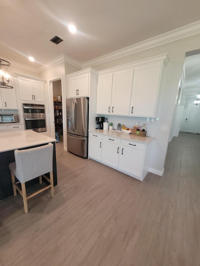 kitchen with visible vents, light wood finished floors, light countertops, appliances with stainless steel finishes, and white cabinetry