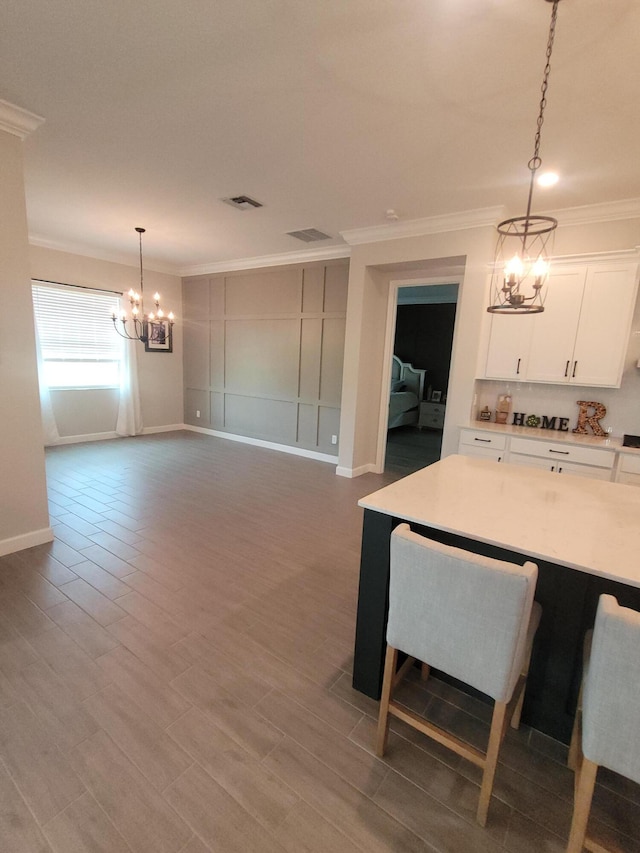 dining space featuring visible vents, a notable chandelier, ornamental molding, wood finished floors, and baseboards