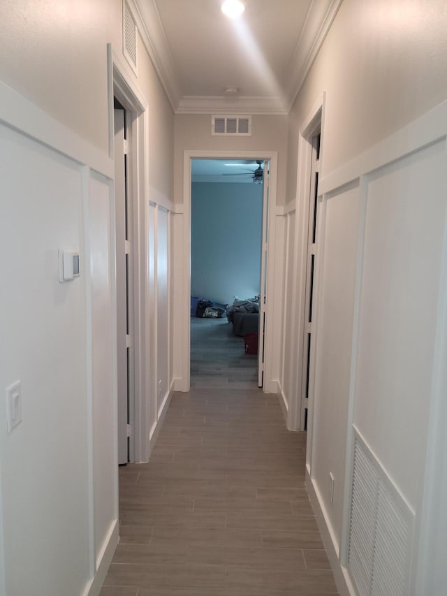 hallway featuring visible vents, ornamental molding, and wood tiled floor