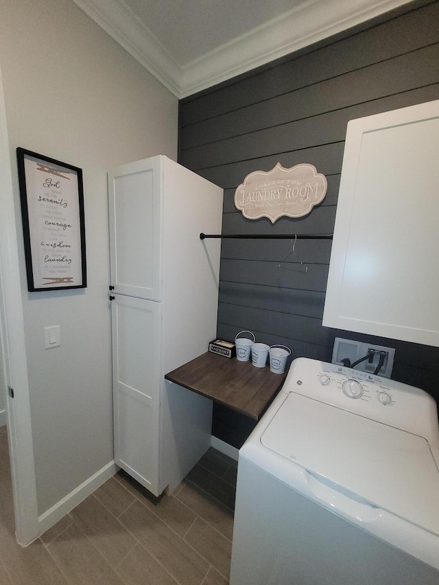 laundry area featuring cabinet space, washer / clothes dryer, wood walls, and ornamental molding