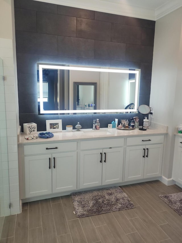 bathroom with tasteful backsplash, vanity, wood finish floors, and ornamental molding