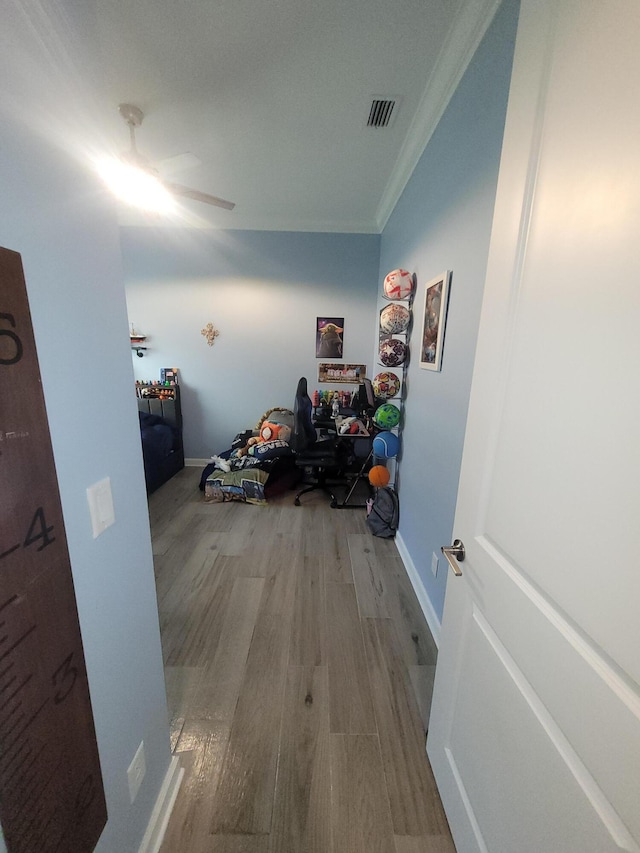 corridor with visible vents, ornamental molding, baseboards, and wood finished floors