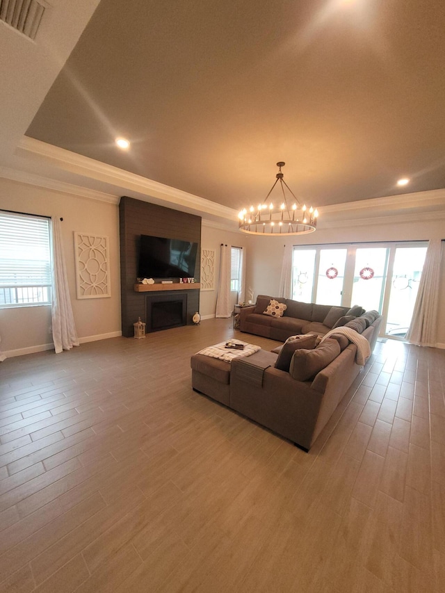 living room with visible vents, plenty of natural light, wood finished floors, and ornamental molding