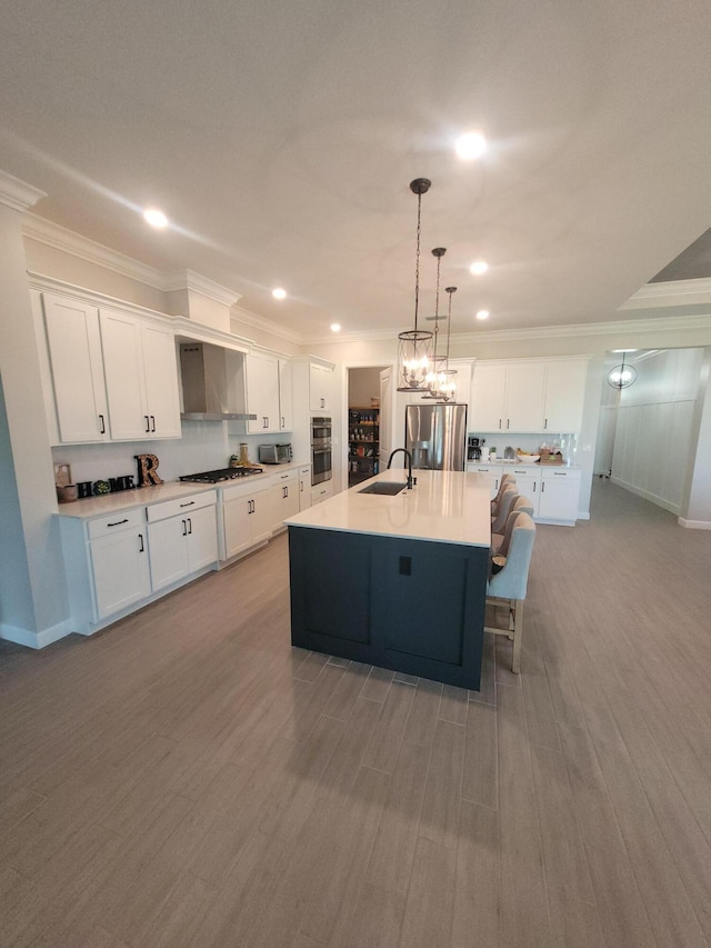 kitchen featuring a sink, white cabinets, crown molding, wall chimney exhaust hood, and stainless steel fridge