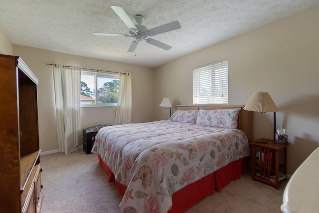 bedroom featuring baseboards, light carpet, a textured ceiling, and ceiling fan