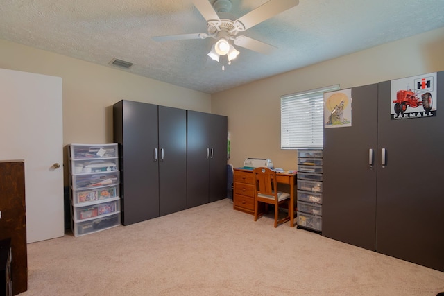 office area featuring a ceiling fan, light colored carpet, visible vents, and a textured ceiling