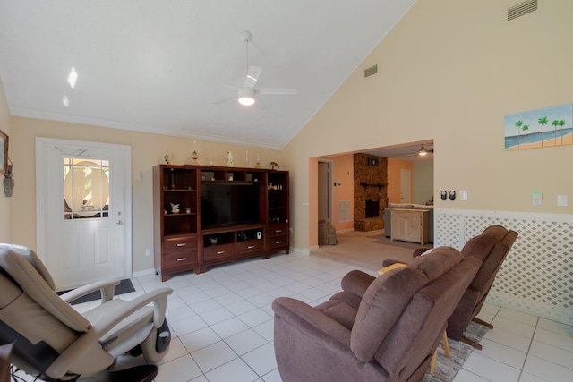 living area featuring a stone fireplace, light tile patterned flooring, visible vents, and ceiling fan