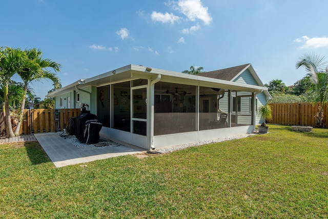 rear view of house with a fenced backyard, a yard, and a sunroom