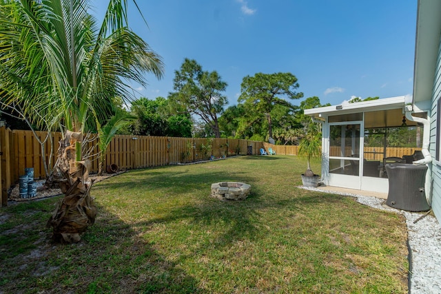 view of yard featuring a fire pit, a fenced backyard, and a sunroom