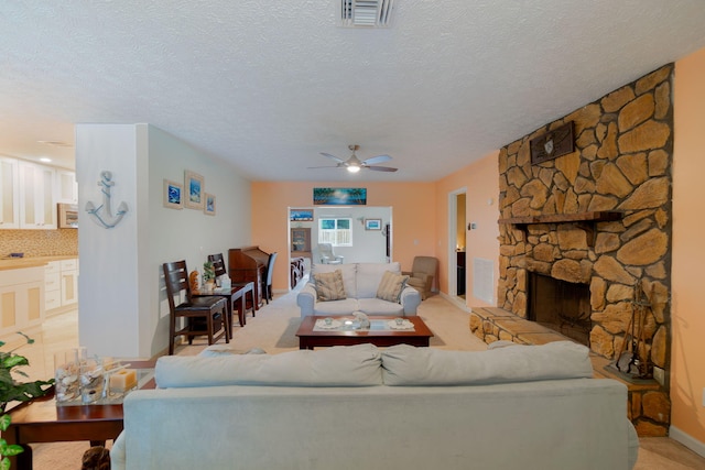 living area featuring light colored carpet, visible vents, a textured ceiling, and a fireplace