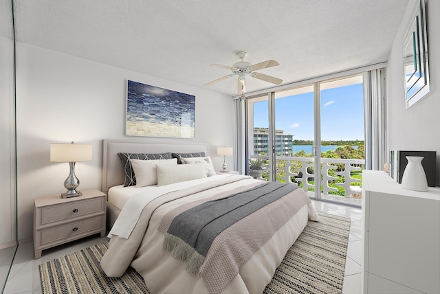 2760 S Ocean Blvd Unit 416, Palm Beach, FL 33480 - bedroom featuring a wall of windows, a water view, light tile patterned flooring, a textured ceiling, and a ceiling fan